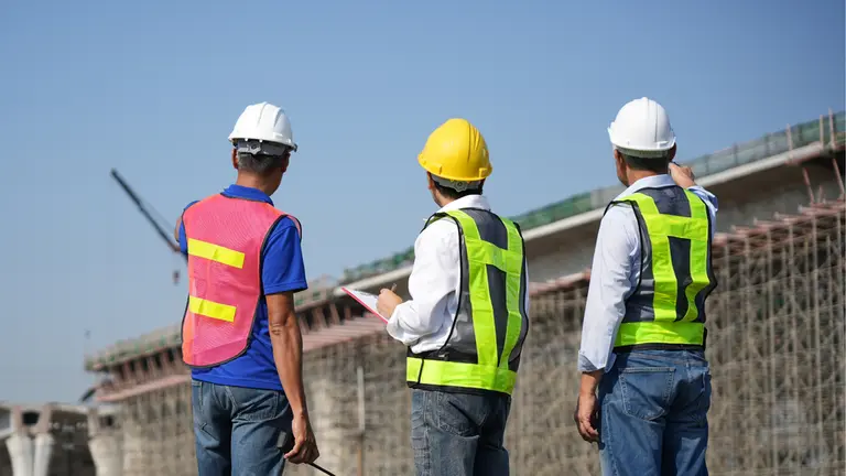 Three team members reviewing the execution of a concrete structure with scaffolding