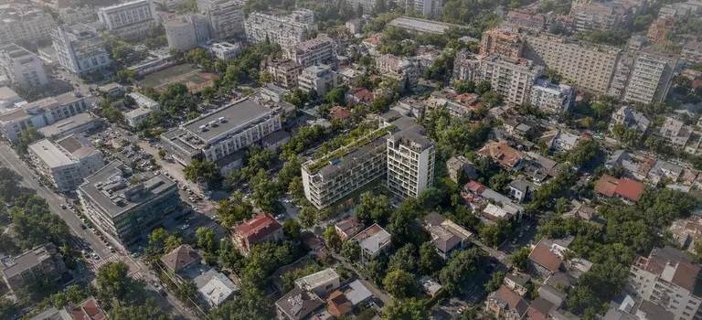 Vedere aeriană a unui cartier bucureștean dens, cu o clădire rezidențială nouă inserată între vile interbelice, blocuri și case existente.